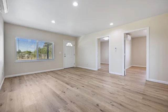 a view of an empty room with wooden floor and window