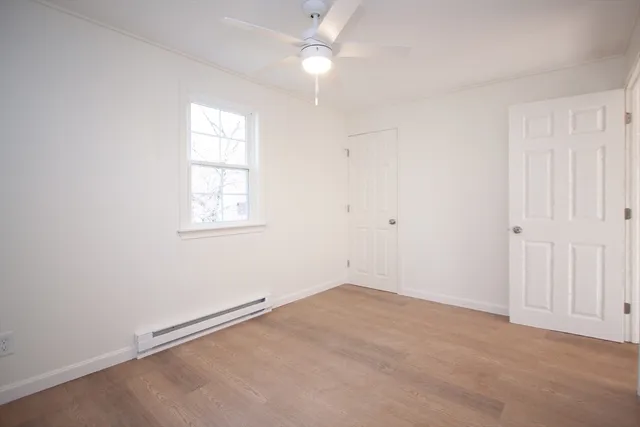 an empty room with windows and fan