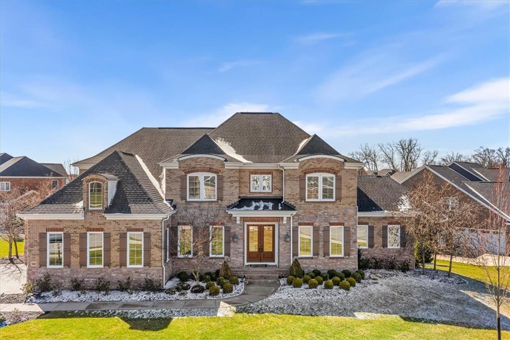 a front view of a residential houses with yard and large trees