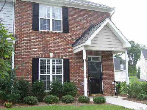 a view of a brick house with yard and plants
