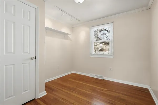 a view of an empty room with wooden floor and a bathroom