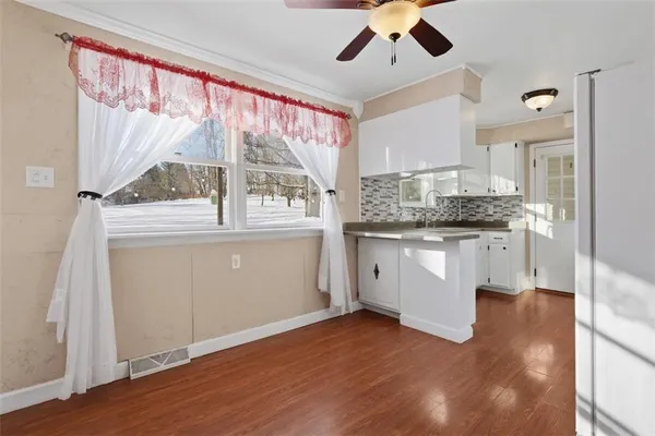 a kitchen with stainless steel appliances granite countertop a refrigerator a microwave oven a sink and white cabinets with wooden floor