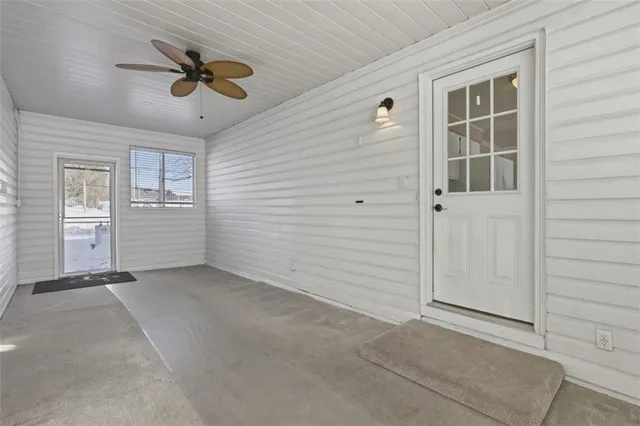 a view of an empty room with wooden floor and chandelier fan