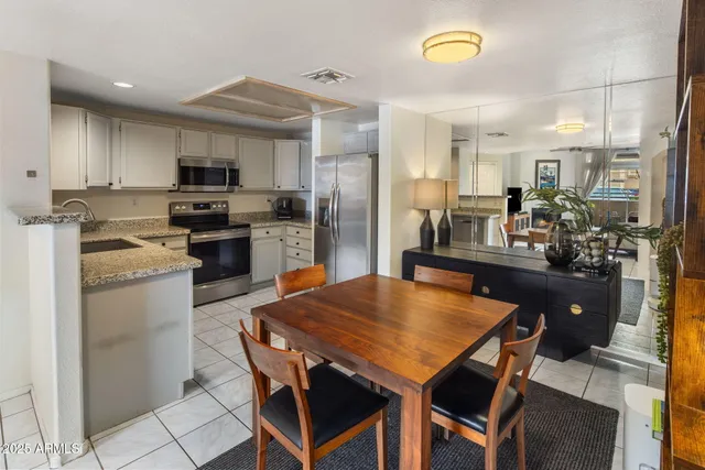 a kitchen with stainless steel appliances granite countertop a stove a refrigerator a sink a dining table and chairs