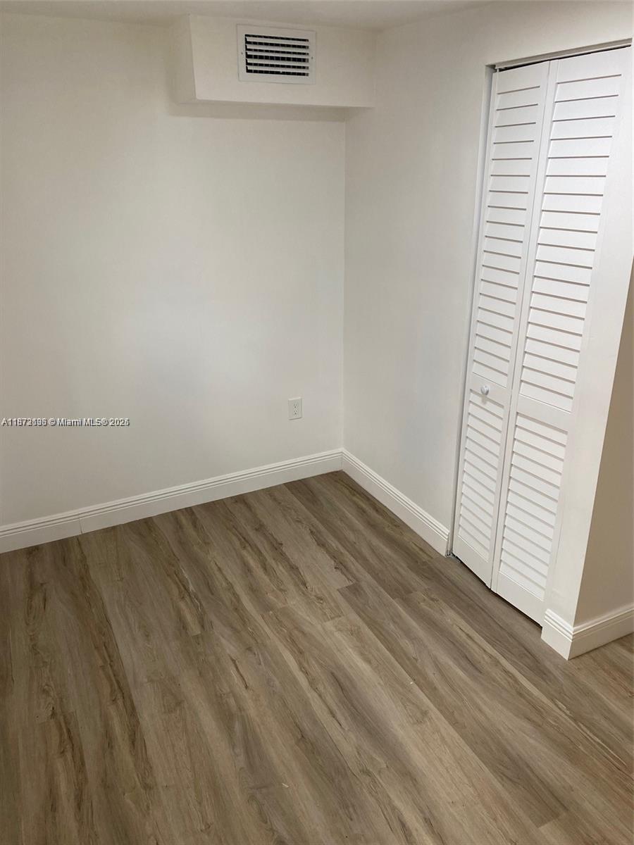 7390 Southwest 30th Terrace, Unit 2 Miami, FL 33155 - Photo 5 of 9 an empty room with wooden floor and windows