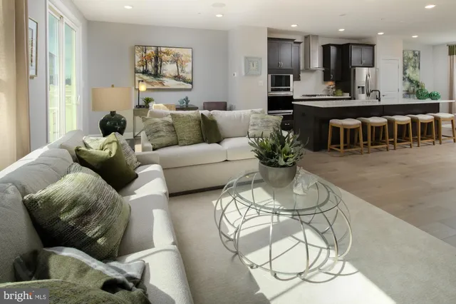 a living room with furniture wooden floor and kitchen view