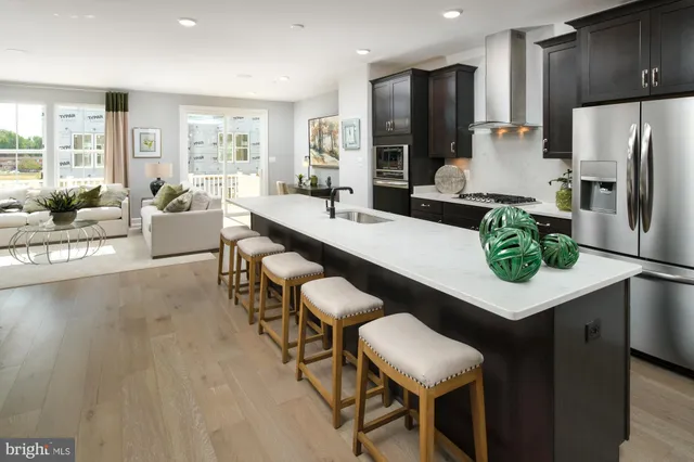 a kitchen with stainless steel appliances a dining table chairs refrigerator and sink