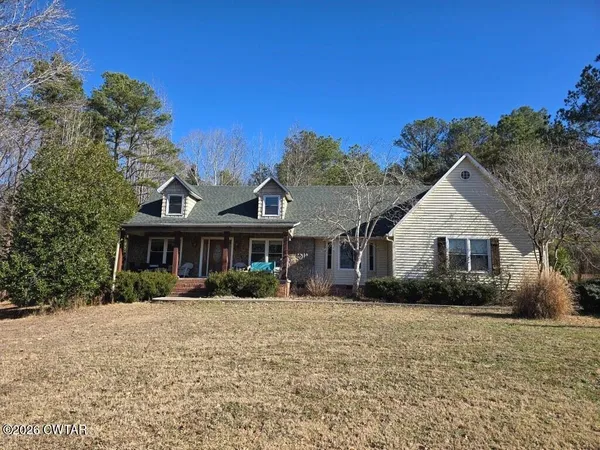 a front view of house with yard and trees in the background