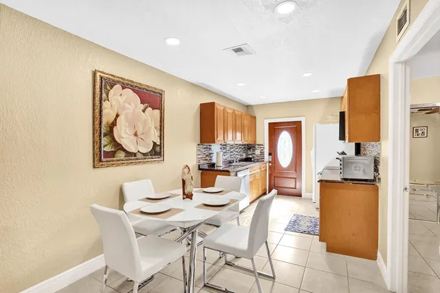 a dining room with kitchen island stainless steel appliances wooden floor dining table and chair