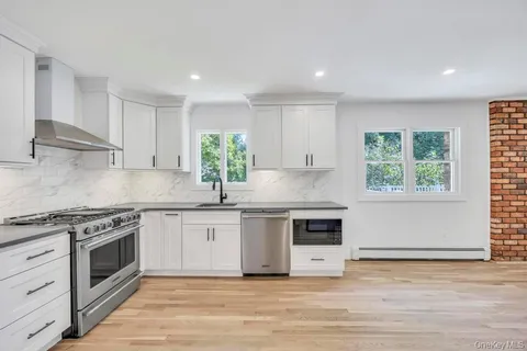 a kitchen with stainless steel appliances granite countertop a stove and white cabinets