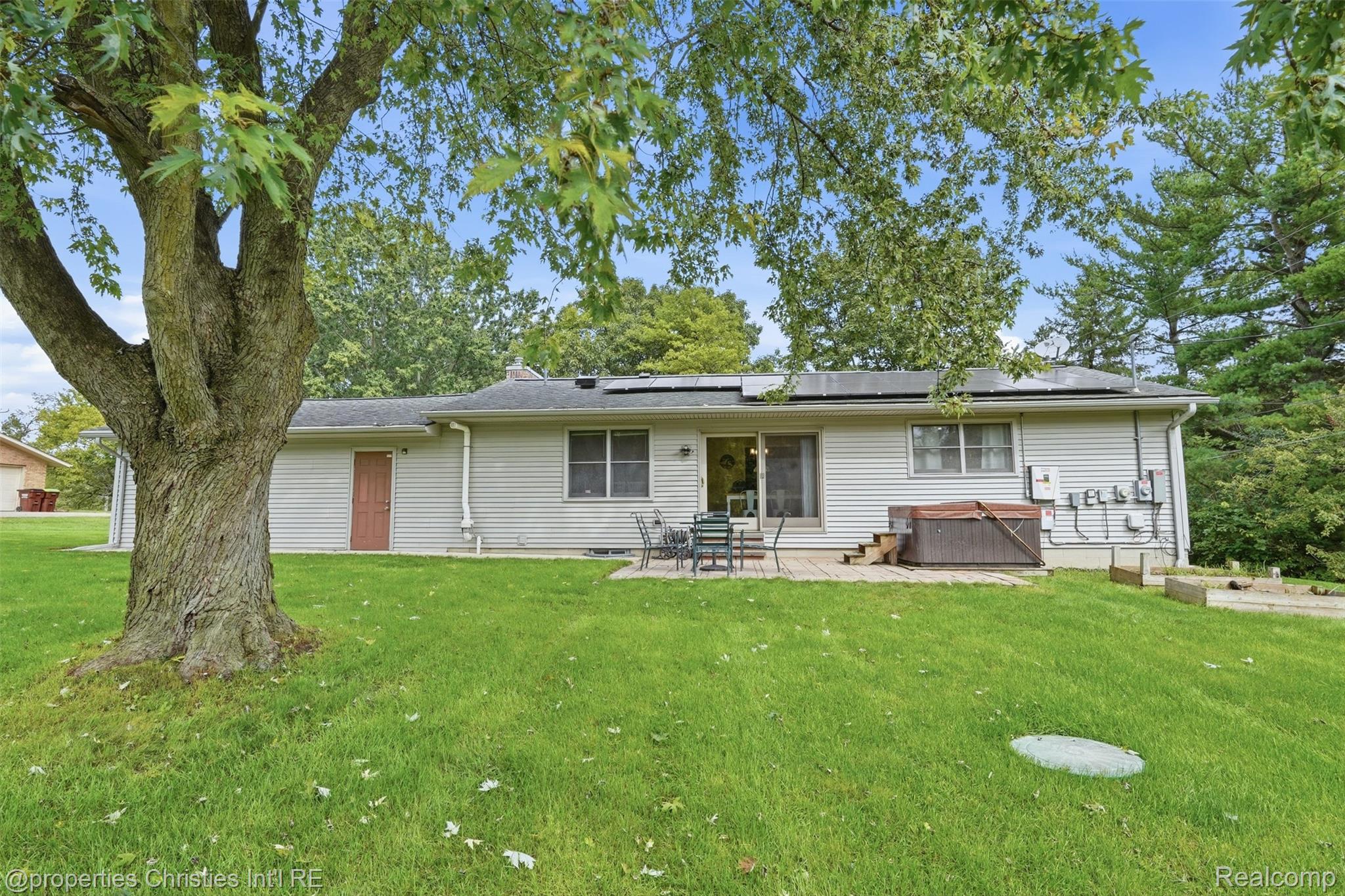 4030 Textile Road Ypsilanti, MI 48197 - Photo 41 of 58 Rear exterior featuring white horizontal siding, a stone patio, sliding glass doors, and a wood-toned hot tub