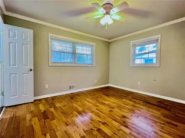 a view of an empty room with window and chandelier fan