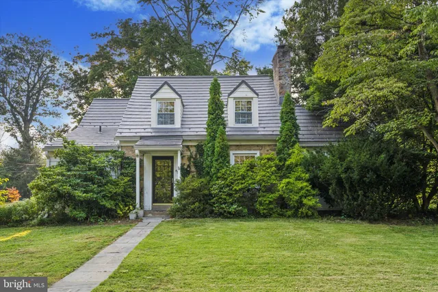 a view of a white house next to a yard with plants and trees