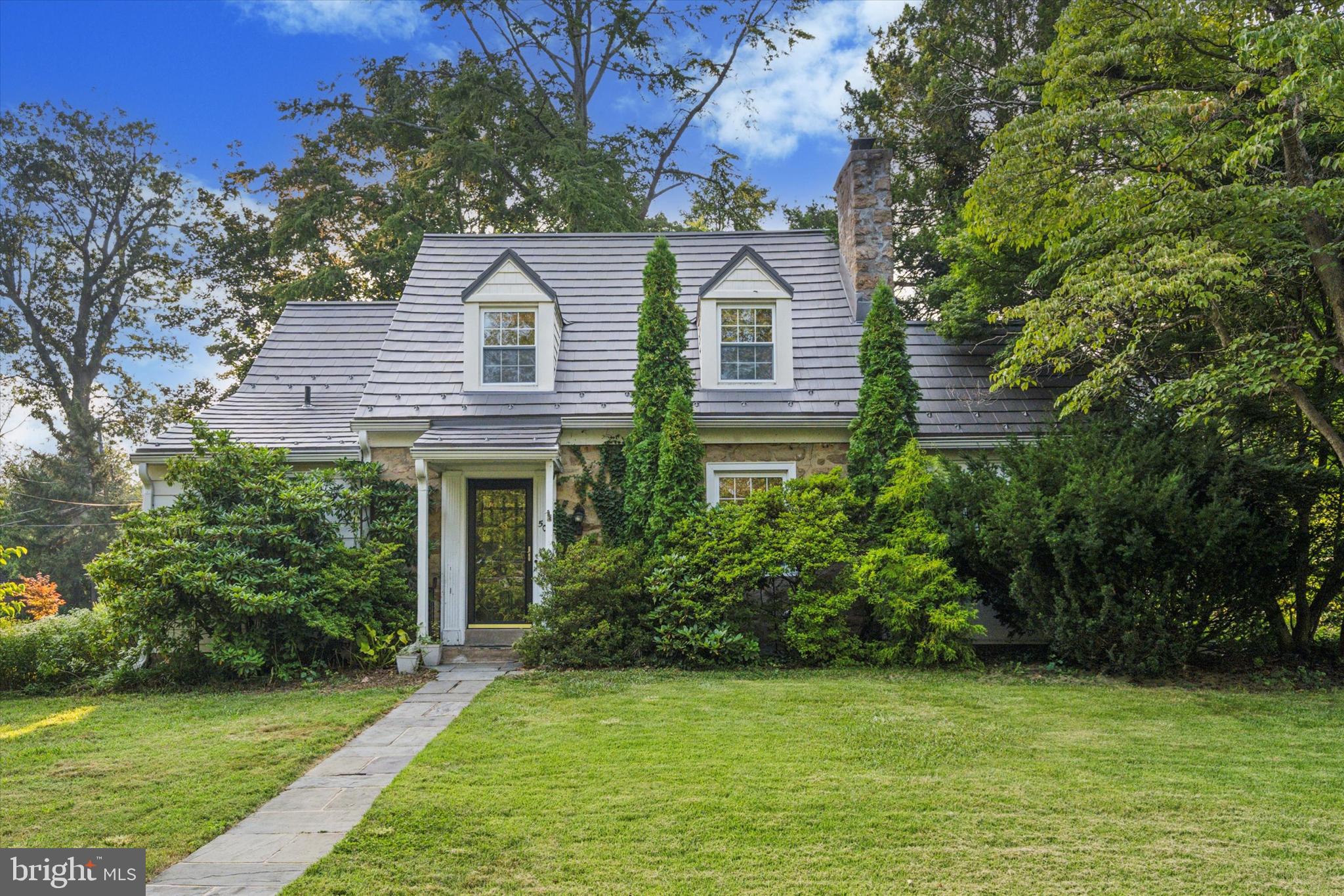 a view of a white house next to a yard with plants and trees