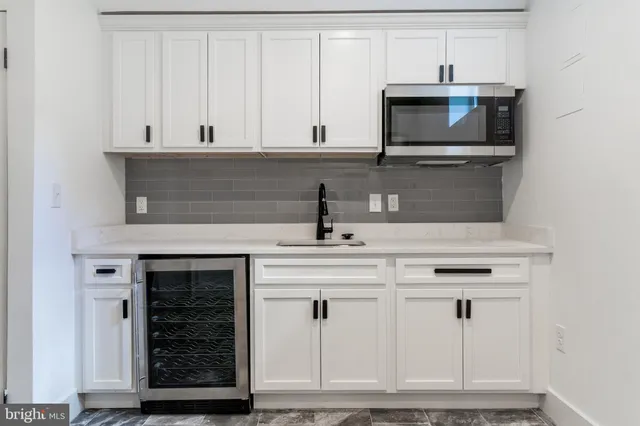 a kitchen with white cabinets and sink
