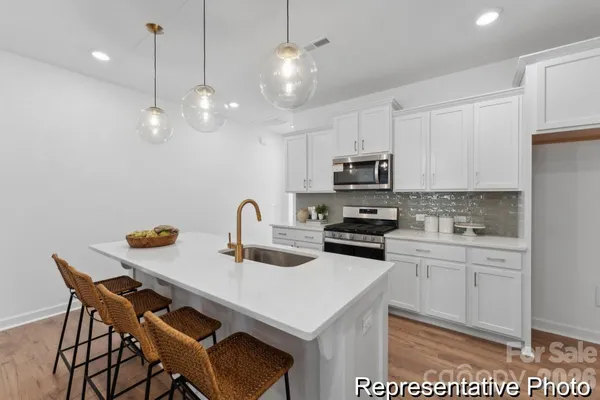 a kitchen with stainless steel appliances kitchen island granite countertop a sink a stove a microwave a refrigerator a kitchen island with chairs and cabinets