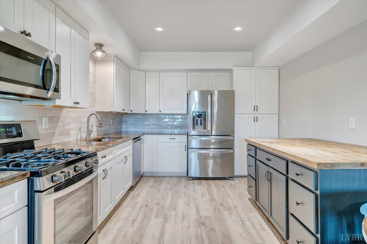 5129 Wheatland Road Bedford, VA 24523 - Photo 39 of 51 a kitchen with stainless steel appliances a stove a sink dishwasher a refrigerator and white cabinets with wooden floor