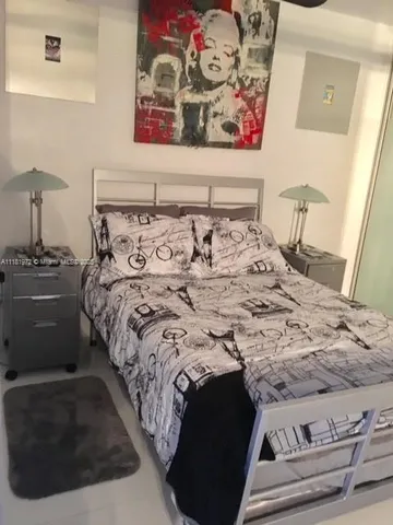 a bedroom with a bed and a lamp on dresser