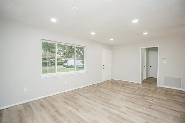 a view of an empty room with wooden floor and a window