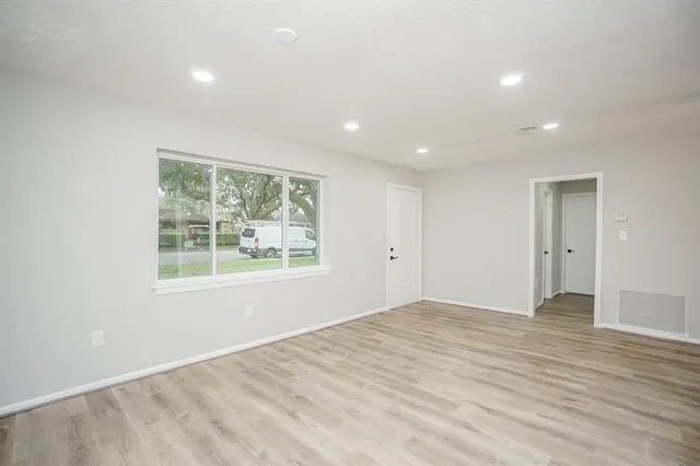 a view of an empty room with wooden floor and a window