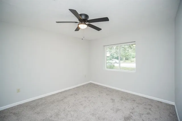 an empty room with a window and a fan