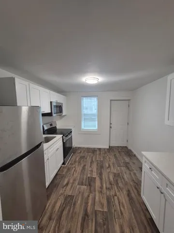 a kitchen with granite countertop a refrigerator stove top oven and sink