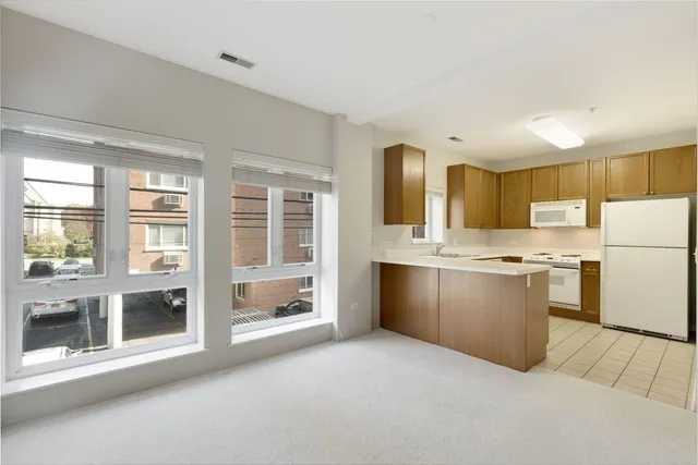 a large white kitchen with granite countertop a sink and a refrigerator