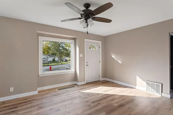 a view of empty room with wooden floor and ceiling fan