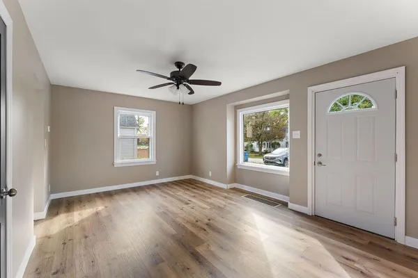 a view of an empty room with a window and wooden floor