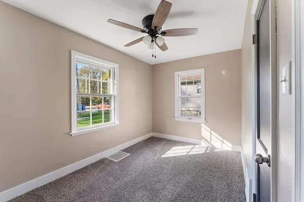 an empty room with windows and fan