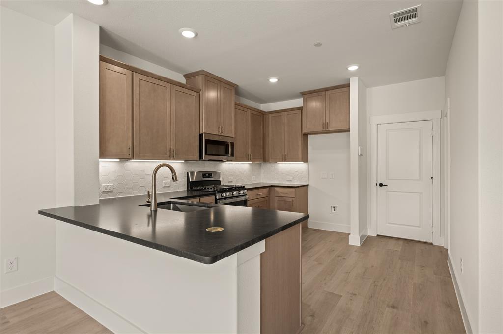 2550 Brunswick Way Allen, TX 75013 - Photo 8 of 24 a kitchen with kitchen island granite countertop a sink stainless steel appliances and cabinets