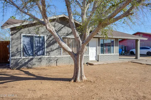 a view of a house with large tree and wooden fence