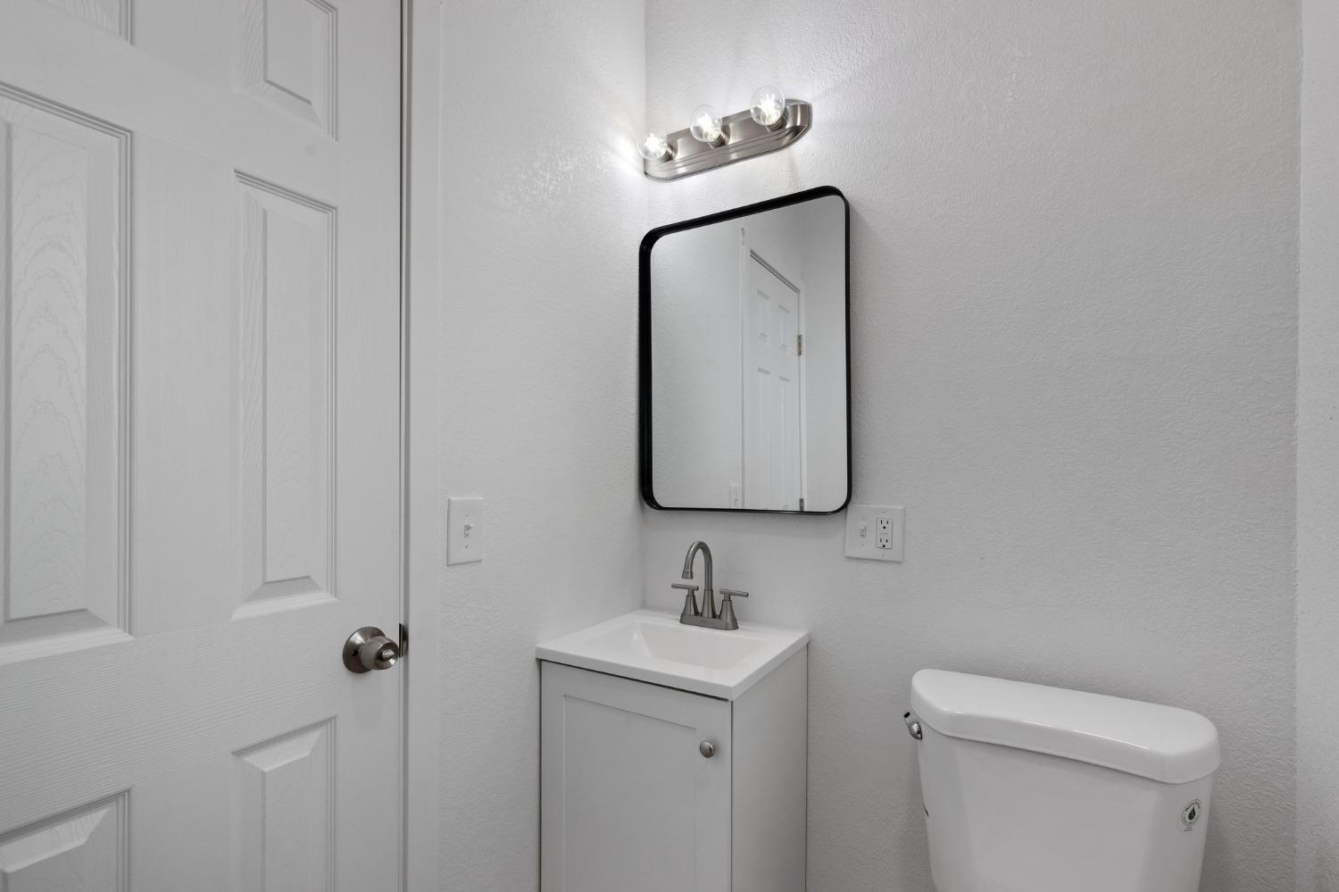 3321 East Montecito Avenue Fresno, CA 93702 - Photo 17 of 22 a bathroom with a toilet sink and mirror