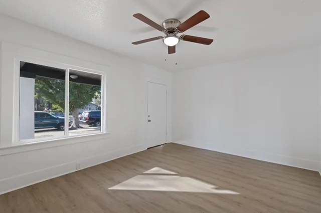 an empty room with wooden floor and windows