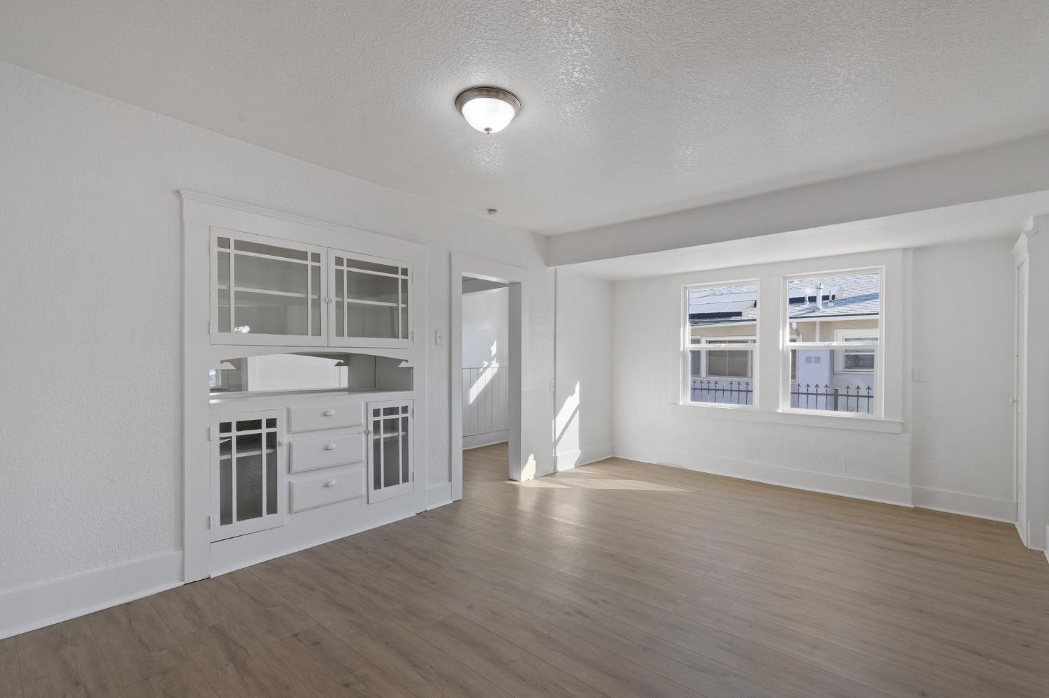 3321 East Montecito Avenue Fresno, CA 93702 - Photo 9 of 22 a view of a kitchen and an empty room with wooden floor and a window
