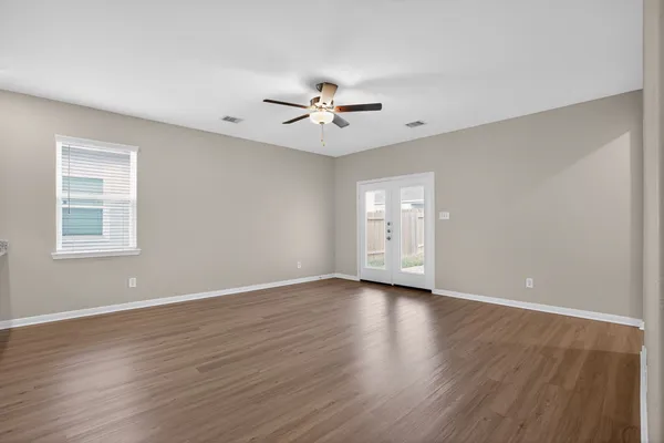 an empty room with wooden floor ceiling fan and windows