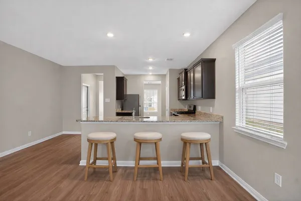 a kitchen with sink a table and chairs in wooden floor