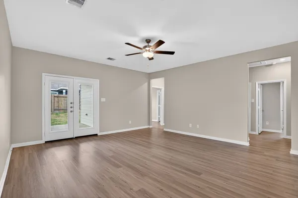 an empty room with wooden floor and a ceiling fan