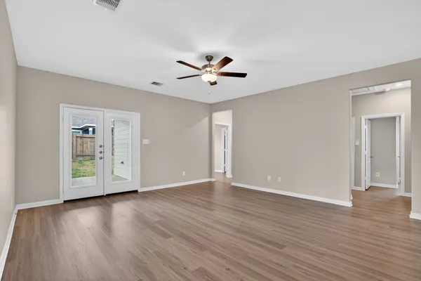 an empty room with wooden floor and a ceiling fan