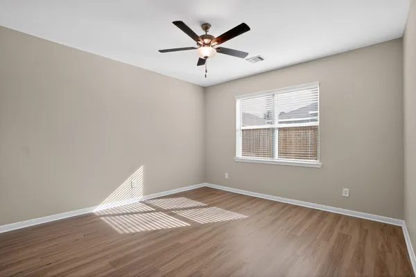 an empty room with wooden floor and windows