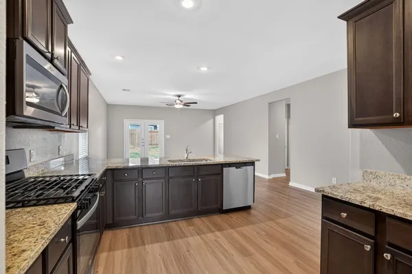 a large kitchen with wooden floors and stainless steel appliances