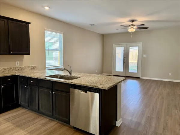 a kitchen with a granite countertop sink cabinets and wooden floor