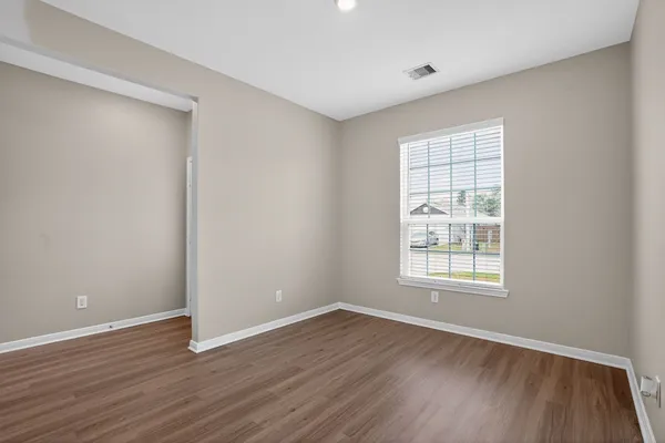 an empty room with wooden floor and windows