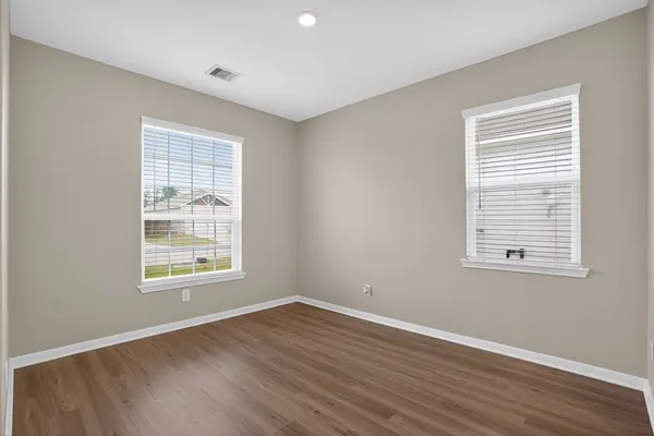 an empty room with wooden floor and windows