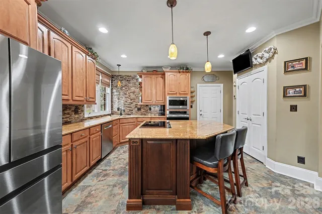 a kitchen with stainless steel appliances granite countertop a sink a stove a refrigerator and island with wooden floor