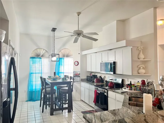 a kitchen with stainless steel appliances kitchen island granite countertop a refrigerator a stove a sink a dining table and chairs with wooden floor
