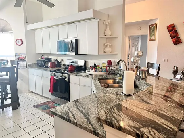 a kitchen with a sink dishwasher a stove top oven a dining table and chairs