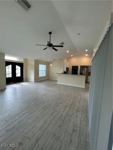 a view of a hallway with wooden floor and a kitchen