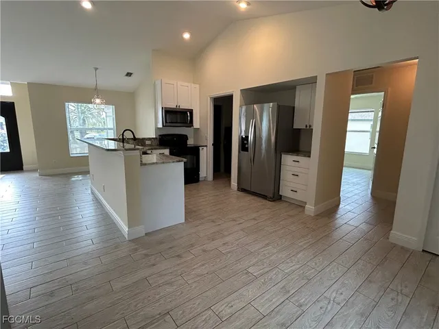 an open kitchen with wooden floor and refrigerator