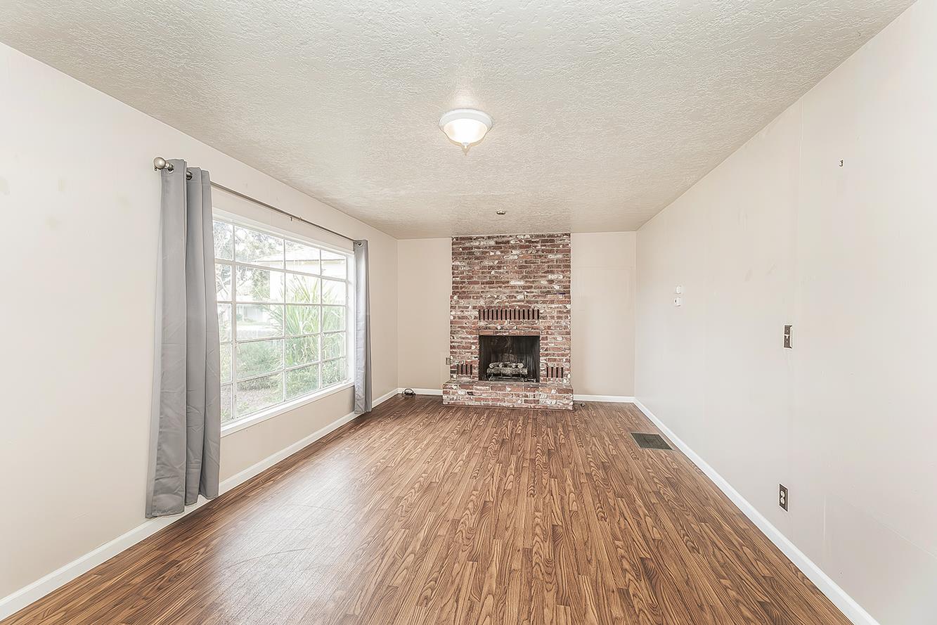 795 West Palm Avenue Reedley, CA 93654 - Photo 3 of 28 an empty room with wooden floor fireplace and windows